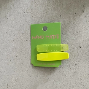 Vue détaillée de barrettes géométriques vert néon et jaune vif sur une carte d'affichage
