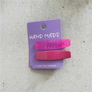 Détail de barrettes en résine rose sur carte violette sur fond de texture ciment gris