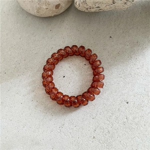 Détail d'un élastique spirale ambre translucide sur une surface en pierre grise
