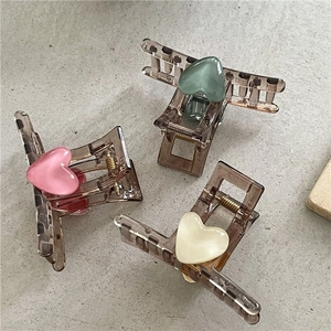 Close-up of translucent brown hair claws with heart resin stone inlay in three colors