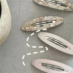 Dettaglio di fermagli per capelli ovali in acetato con trama marmorea e floreale