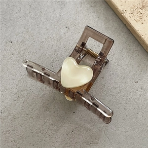 Close-up of translucent brown hair claw clip featuring a pearlescent white heart detail