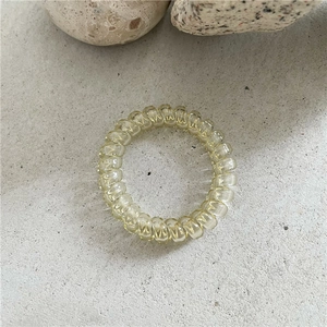 Détail d'un élastique spirale jaune translucide sur un fond de pierre minimaliste