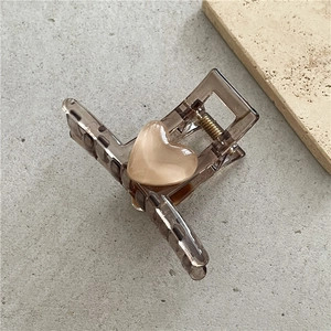 Macro detail of amber brown hair claw clip featuring a cream heart-shaped opal stone