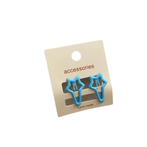 Pair of blue star-shaped metal hair clips for girls on a handmade card display