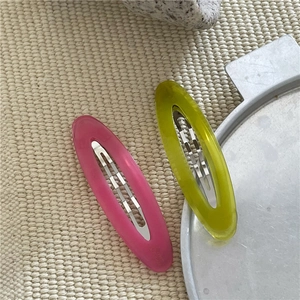 Dettaglio di fermagli per capelli ovali in acetato rosa e giallo con molle in metallo