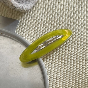 Dettaglio di un fermaglio per capelli ovale traforato in acetato verde-giallo traslucido