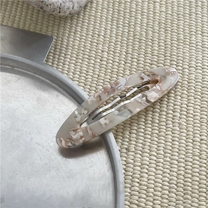 Dettaglio del fermaglio per capelli in acetato marmorizzato su vassoio metallico