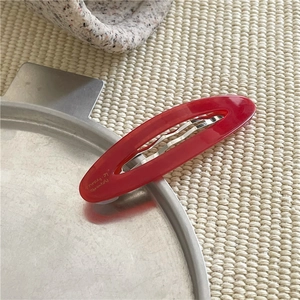 Dettaglio della clip per capelli in acetato rosso con testo francese su vassoio