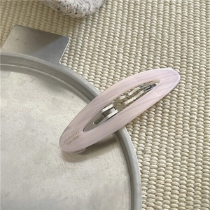 Dettaglio del fermaglio per capelli ovale in acetato con trama in marmo rosa