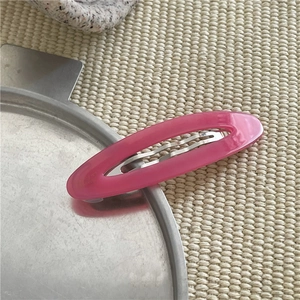 Dettaglio di un fermaglio per capelli ovale in acetato rosa con molla in metallo argento