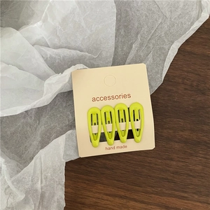 Detail view of 4-pack lime green metal snap hair clips on cardboard display card