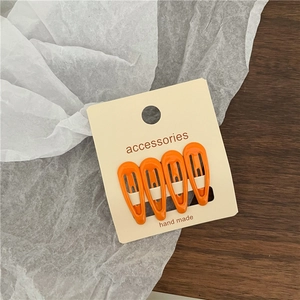 Set of four orange enamel mini water drop hair clips on a cream-colored display card
