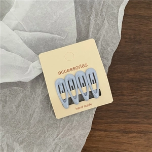 Detail of four mini light blue water drop hair clips on a beige display card