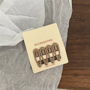 Set of 4 brown matte lacquer snap hair clips on a minimalist beige card accessory