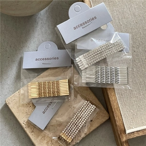 Elegant set of silver and gold metal bobby pins with rhinestones on a decorative base