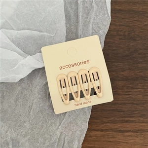 Set of four cream-colored metal lacquer drip hair clips displayed on a retail card
