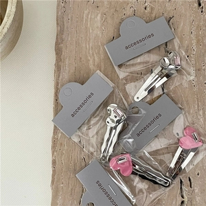 Détail de barrettes à cheveux en cœur avec strass sur carte d'accessoires grise