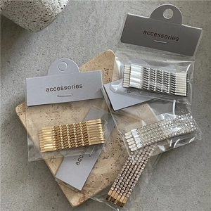 Detail of silver rhinestone twist hair clips set with minimalist packaging on stone