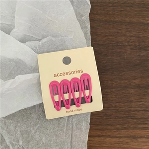 Set of four glossy pink lacquer metal snap hair clips on cream-colored card packaging