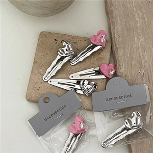 Détail de barrettes à cheveux cœur en strass argentés et émail rose sur fond bois esthétique