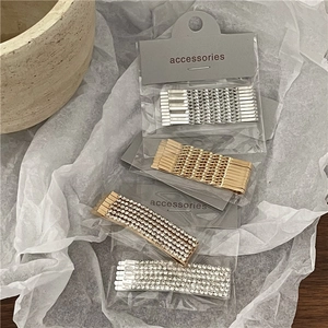 Detailed view of silver twist hairpins and rhinestone barrettes set on paper