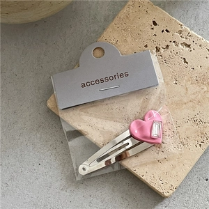 Détail d'une pince à cheveux cœur rose avec strass sur clip BB argenté et carte support