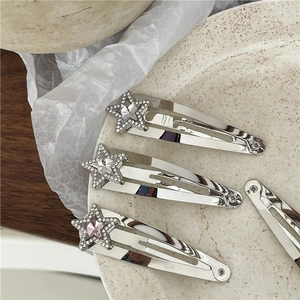 Detalle macro de horquillas de estrella plateadas con pedrería brillante y clip BB de metal