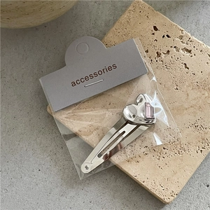 Détail de la pince à cheveux cœur argentée avec strass rose rectangulaire sur carte