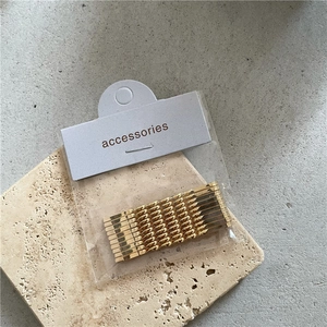 Set of 10 golden alloy hairpins with smooth and twisted designs on beige stone plate