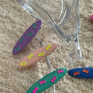 Close-up of colorful alloy hair clips with embossed bow designs in four vibrant matte colors
