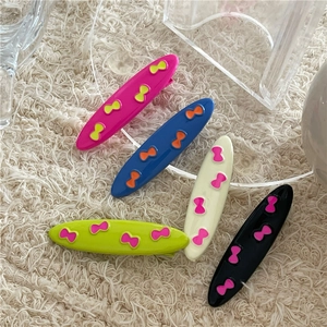 Set of five colorful bow-knot hair clips on a soft plush background for women