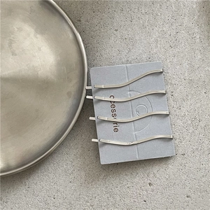 Set di quattro fermagli per capelli ondulati argento disposti su cartoncino grigio