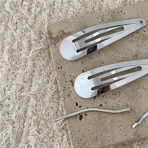 Dettaglio di fermagli per capelli BB in lega d'argento e forcine ondulate su fondo pietra