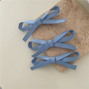 Detailed view of three blue fabric bow hair clips in a stylish set for women