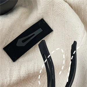 Detail showing the matte texture and curved structure of the black rectangle hair clip