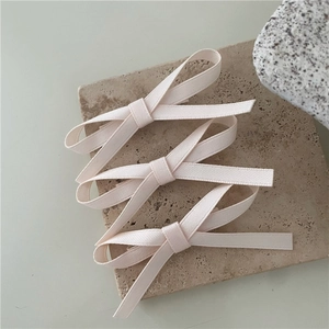 Detailed macro view of three cream fabric bow hair clips on a textured stone surface