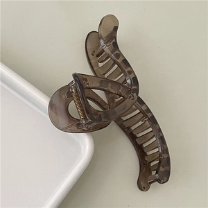 Détail d'une pince à cheveux en acrylique marron écaillé avec ressort métallique doré