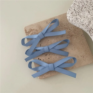 Close-up of three blue ribbon bow hair clips on a decorative stone slab