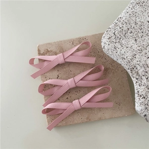 Detailed view of three pink grosgrain ribbon bow hair clips on a textured stone plate