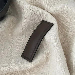 Detail view of dark brown faux leather hair clip with rectangular quilted pattern