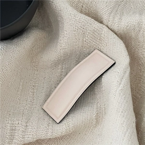 Detail shot of a cream-colored PU leather rectangular hair clip with neat stitching