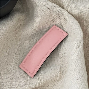 Detailed close-up of a pink faux leather rectangular hair clip with neat stitching