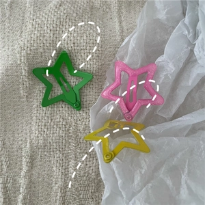 Close-up of sparkling star-shaped BB hair clips in pink, green, and yellow colors