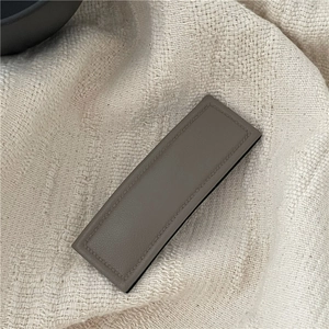 Detailed view of a taupe PU leather rectangular hair clip with fine stitching on knit fabric