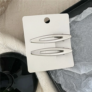 Set aus zwei silbernen matten Haarspangen in hohler Ovalform auf weißer Displaykarte