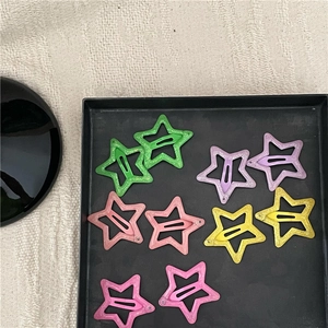 Close-up of colorful glitter star-shaped hair clips in various pastel colors and metallic finish