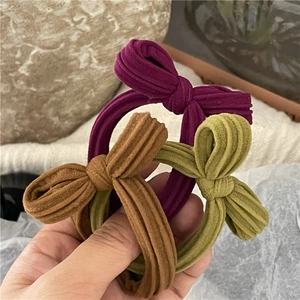 Detailed view of three corduroy bow hair ties in purple, brown, and olive green colors