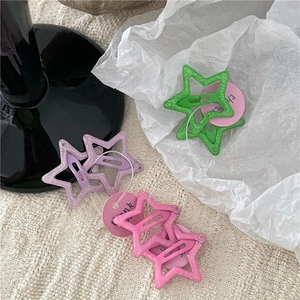 Close-up of glittery hollow star hair clips in green, purple and pink with gift tags