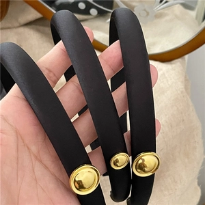 Elegant black satin fabric headband featuring a circular golden metallic accent decoration